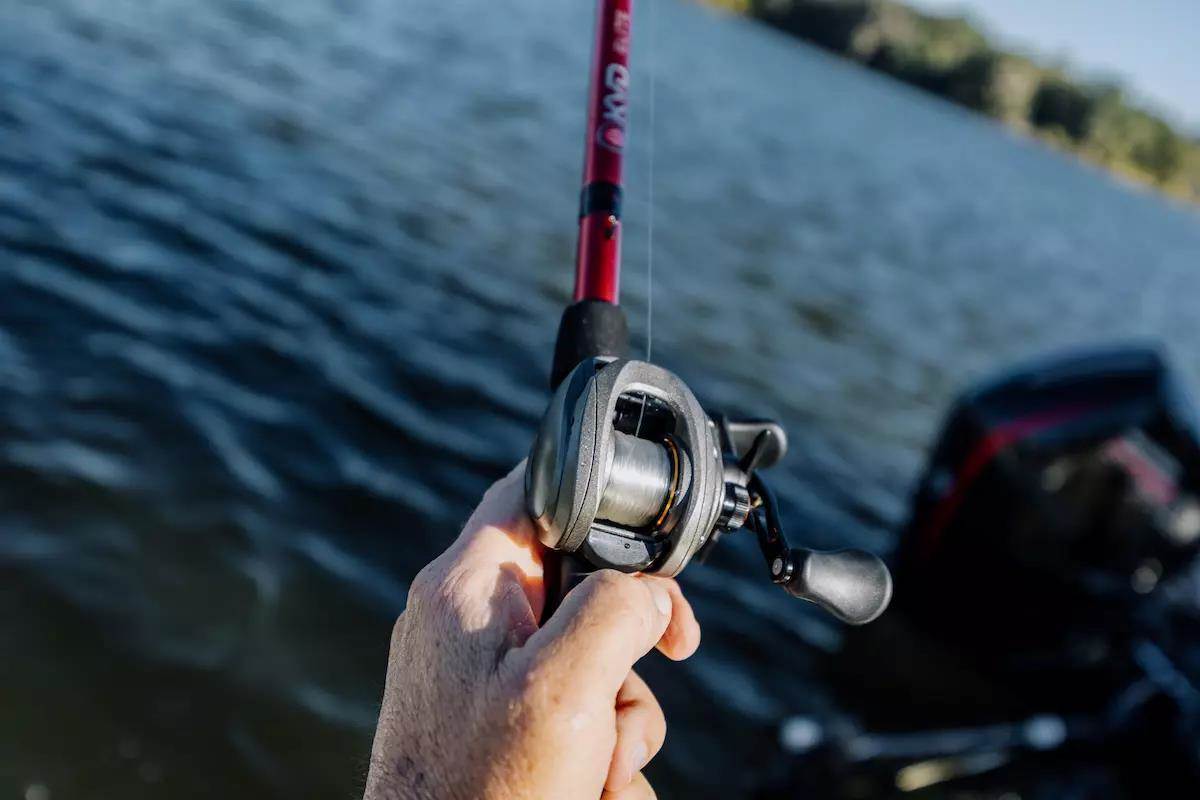 An angler holds a baitcasting rod and reel. 