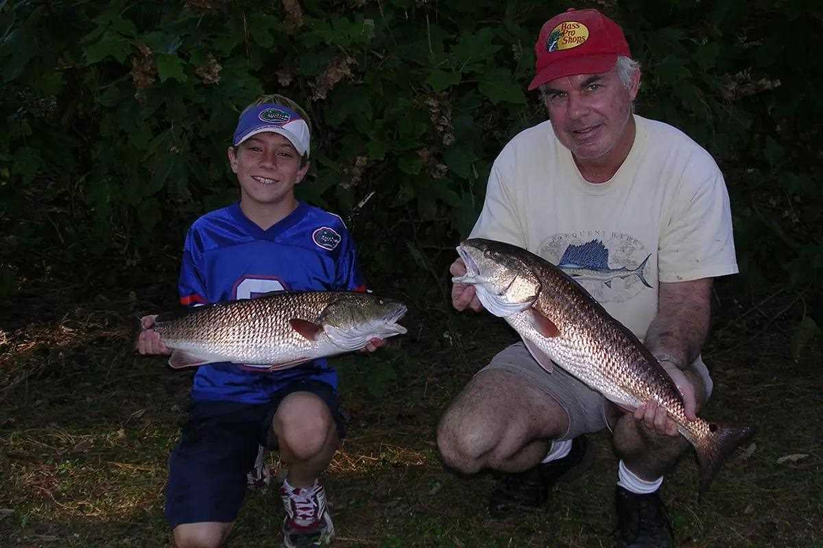 boy and man each holding red drum