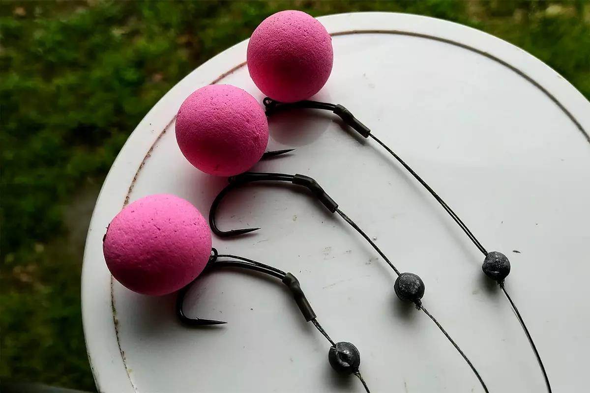 Three carp baits on hooks lie upon a round lid. 