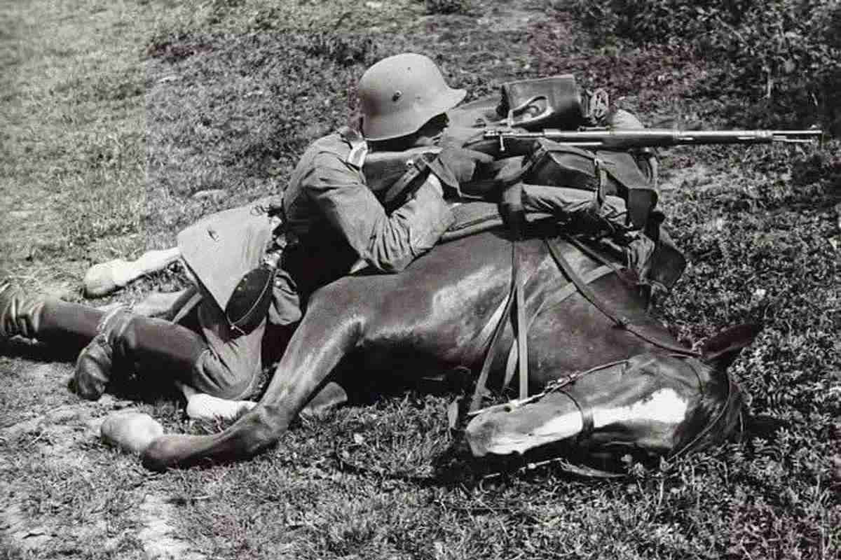 German soldier aiming bolt action Mauser rifle while laying on his horse.