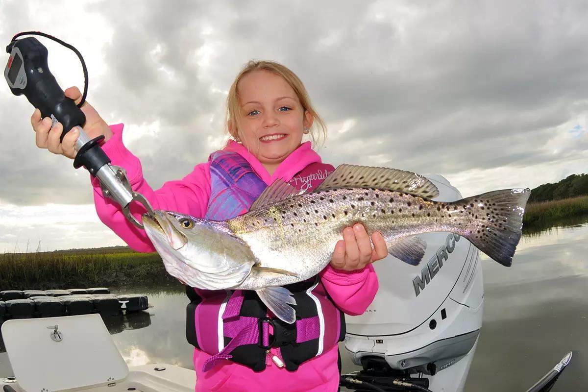 Girl in pink sweatshirt holding large seatrout