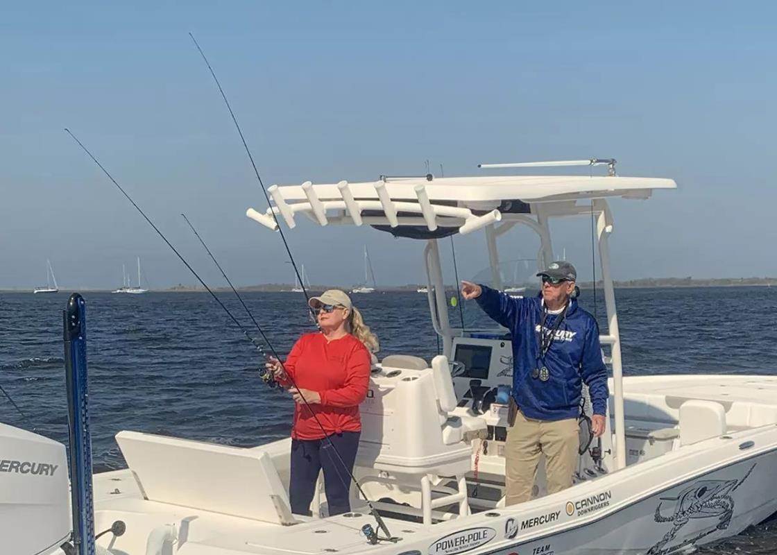 Woman in red shirt and man in blue shirt fishing on a white center console fishing boat