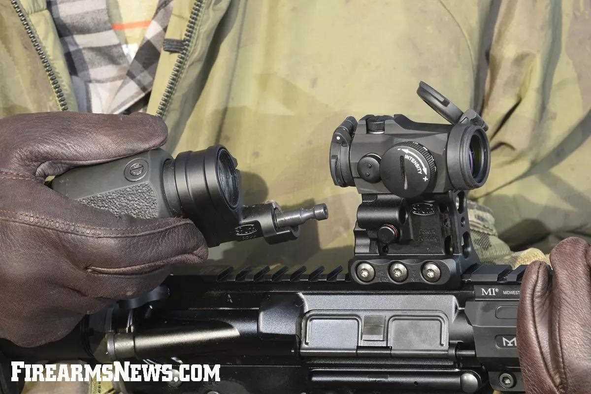 Man hold magnifier next to red dot on rifle