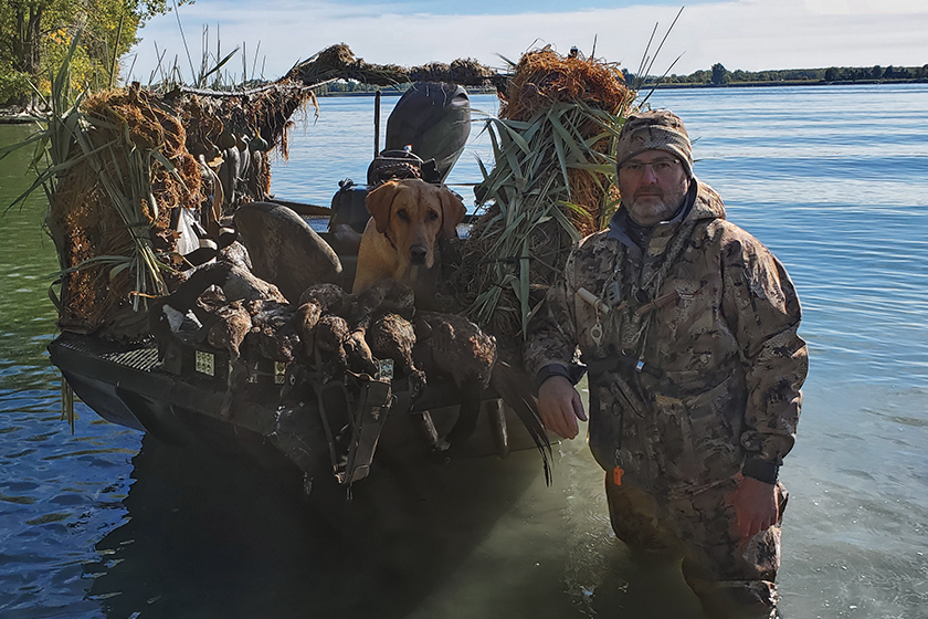 Duck hunter with Labrador and duck boat