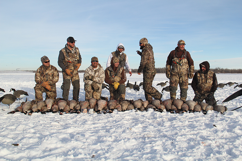 group of hunters with geese in snow