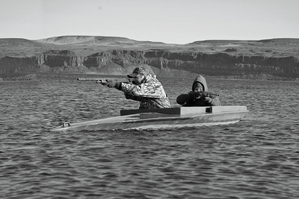 two duck hunters in layout boat