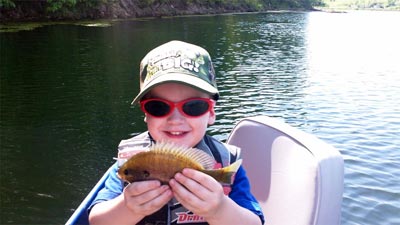 A young angler is delighted to hold up a bluegill.